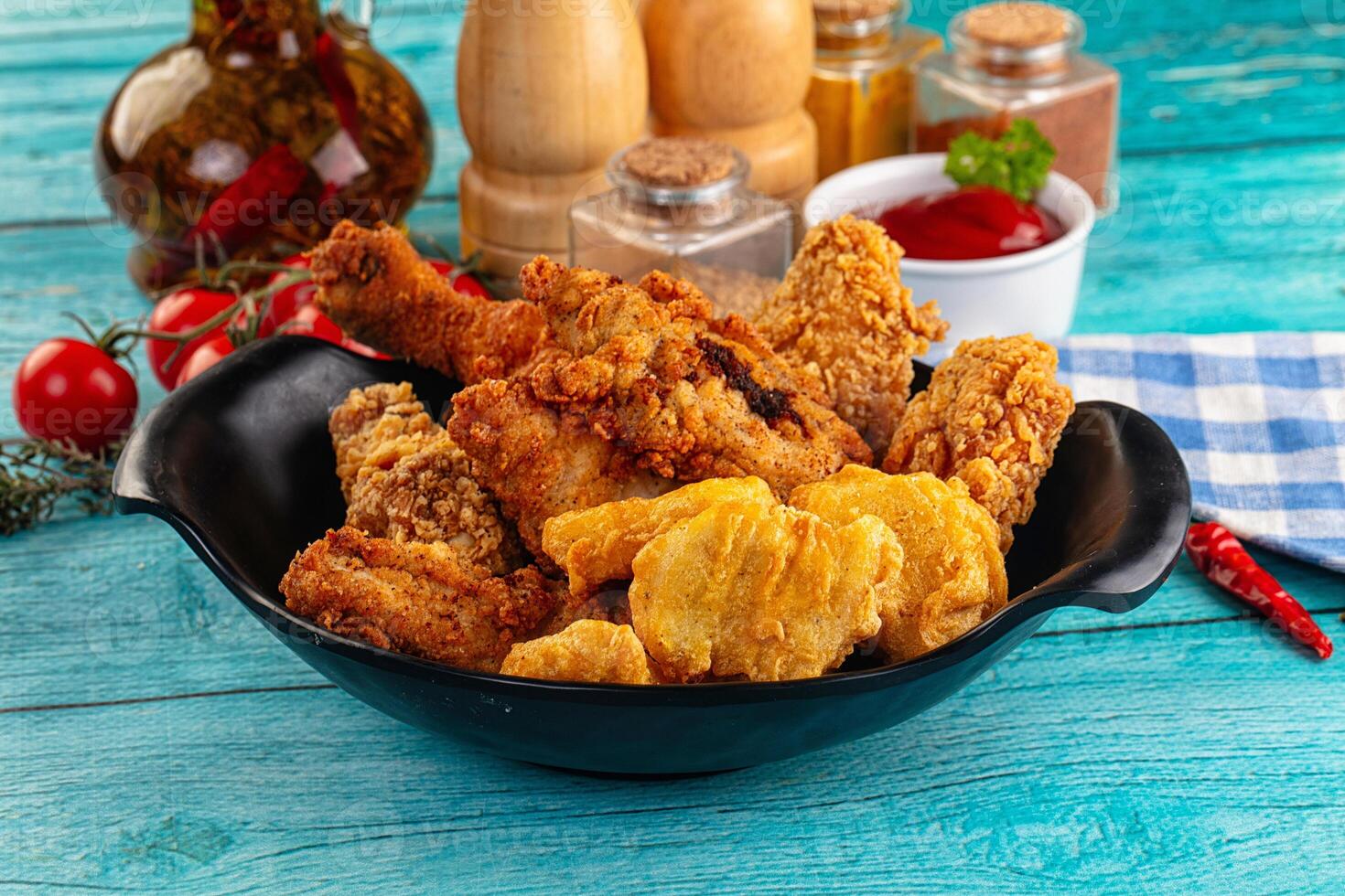 A bowl of fried chicken and other food on a table photo