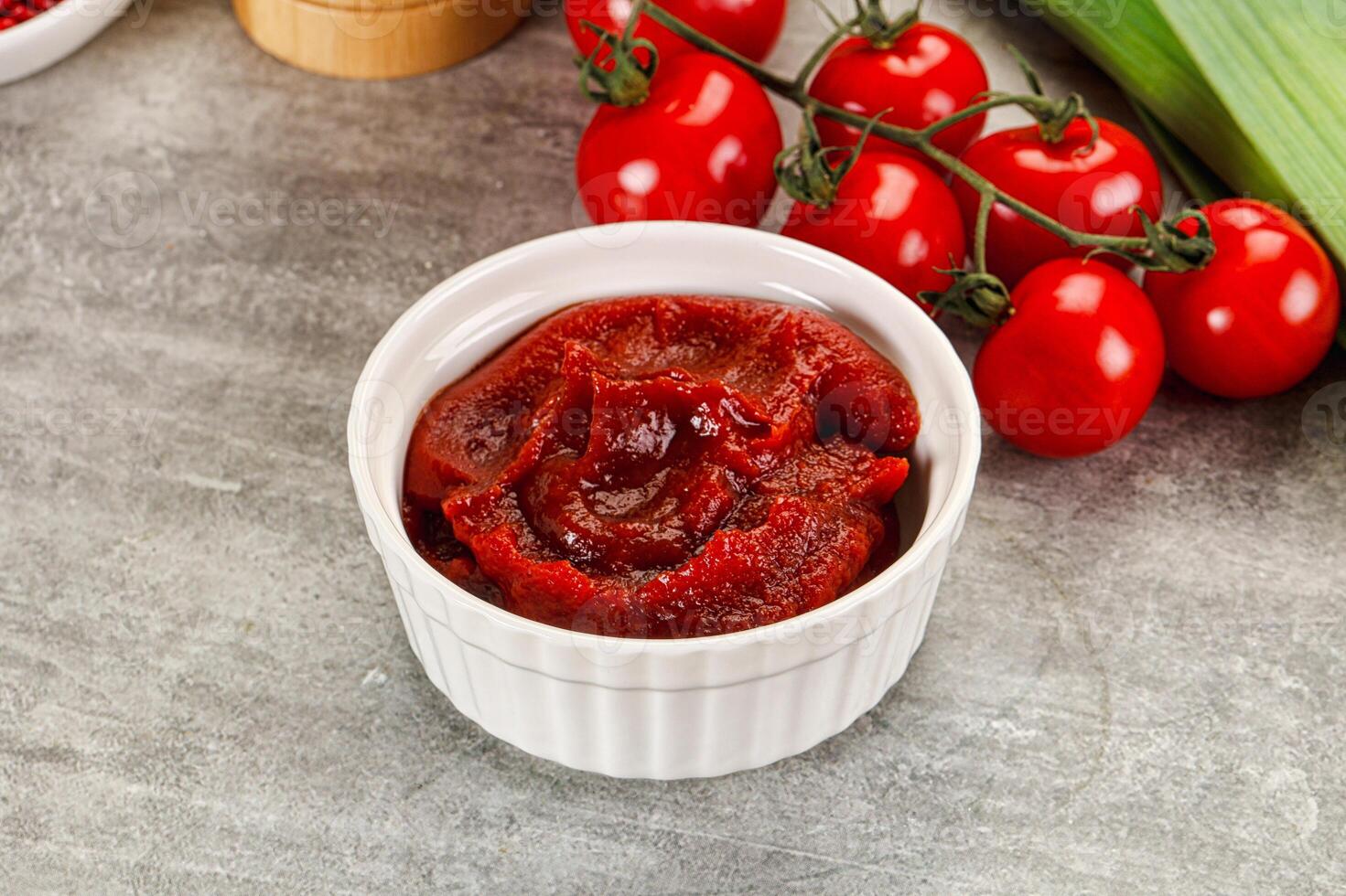 A bowl of tomato sauce next to tomatoes and other vegetables photo