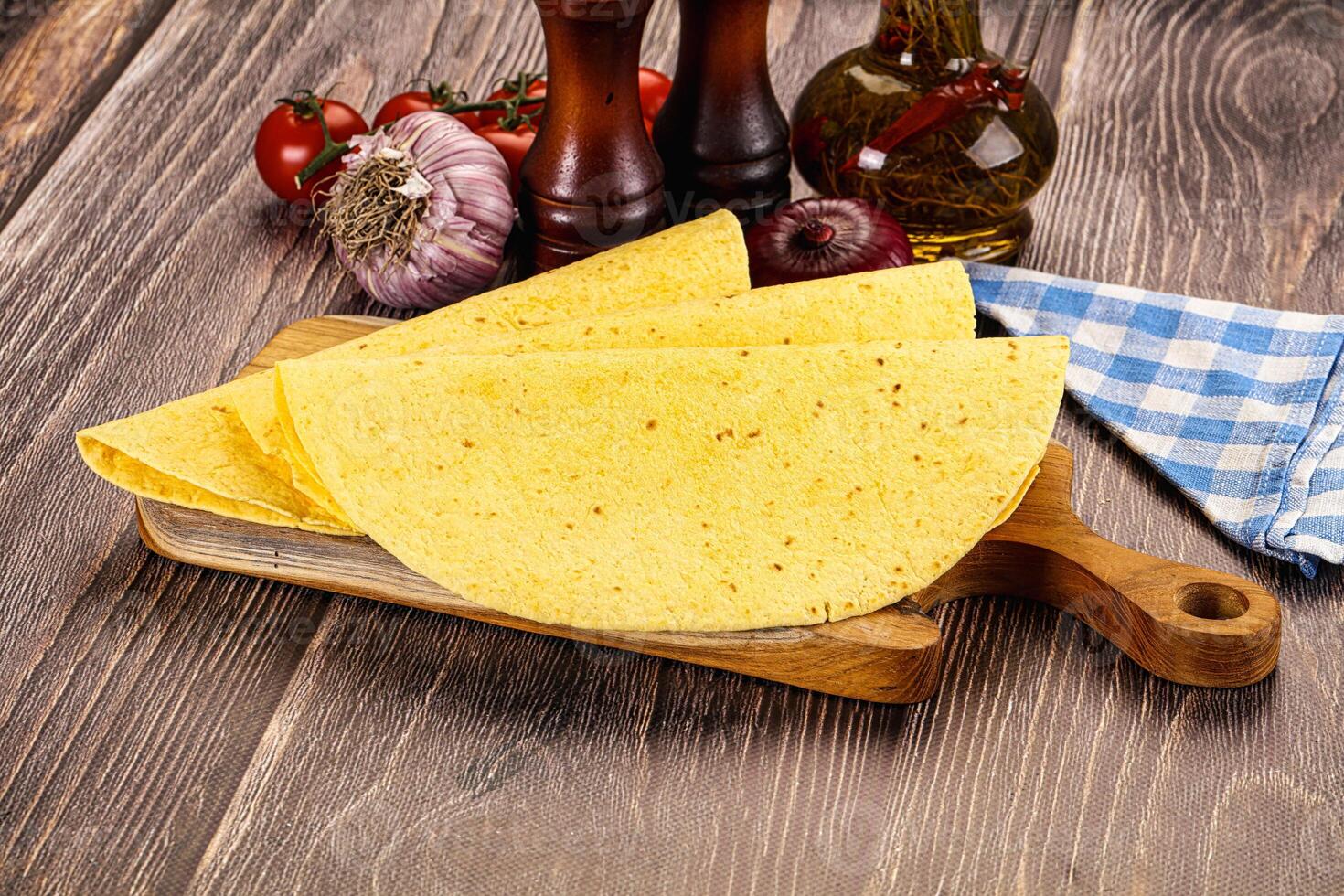 A tortilla on a cutting board with tomatoes, onions and spices photo