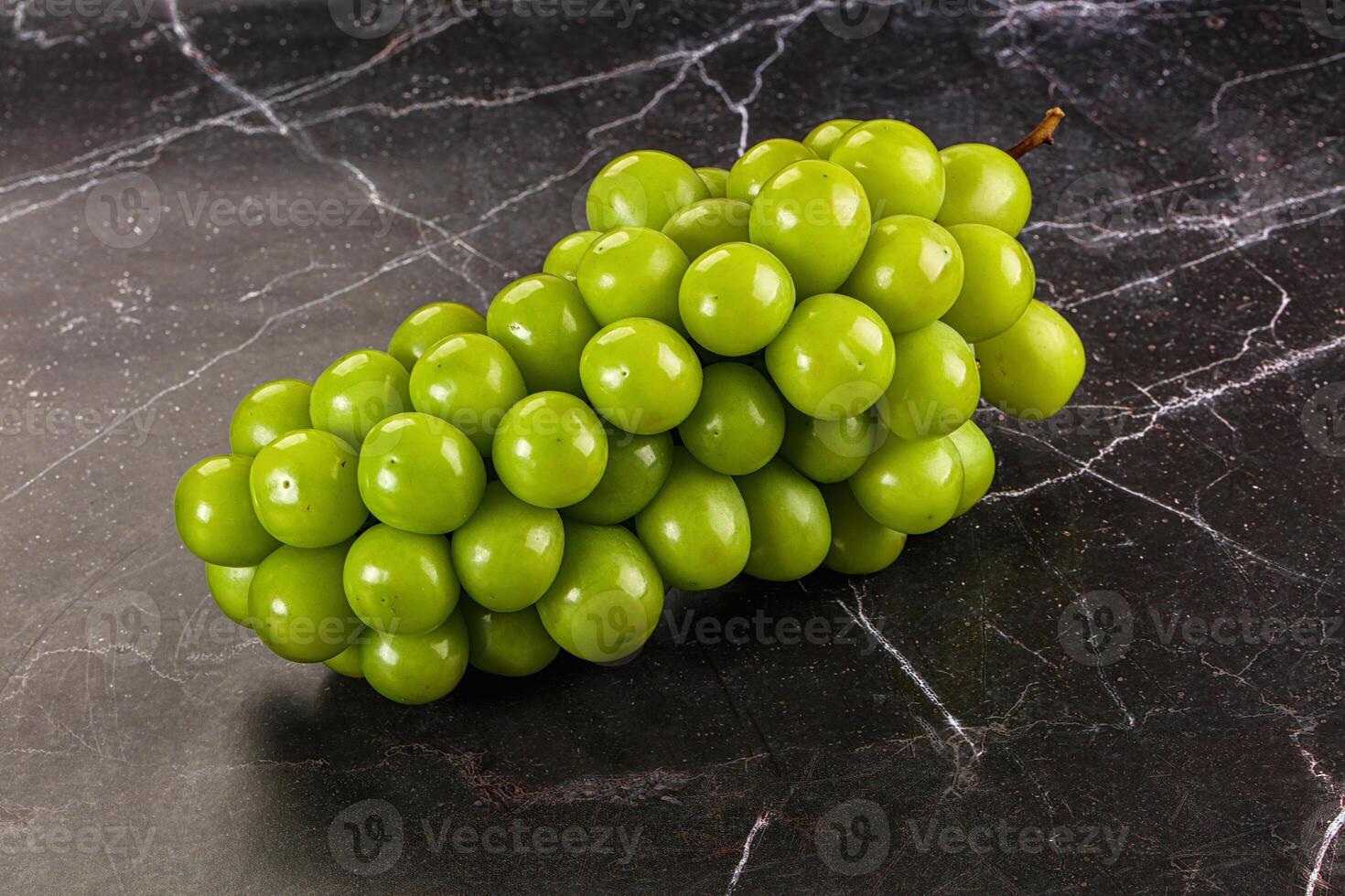 A bunch of green grapes sitting on a marble surface photo