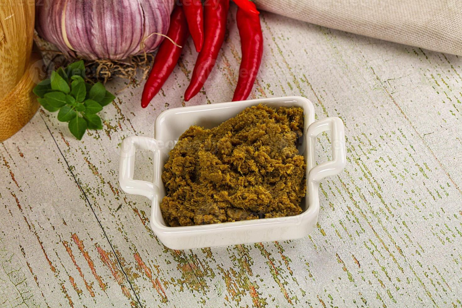 A bowl of spices and herbs on a wooden table photo