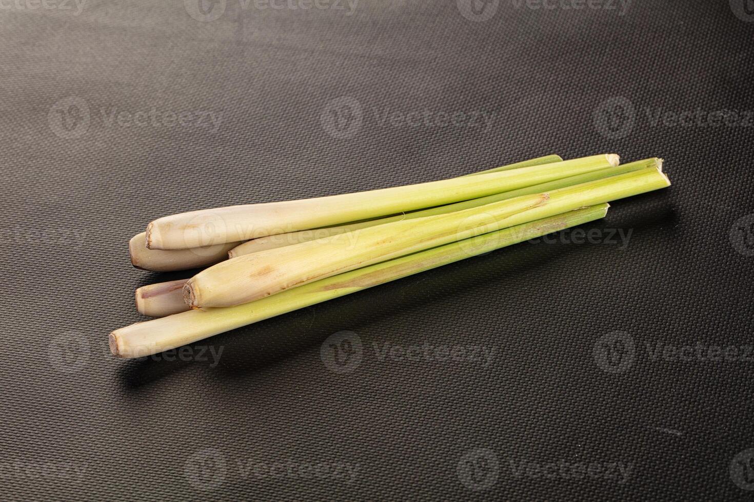 Three pieces of fresh lemongrass on a black surface photo
