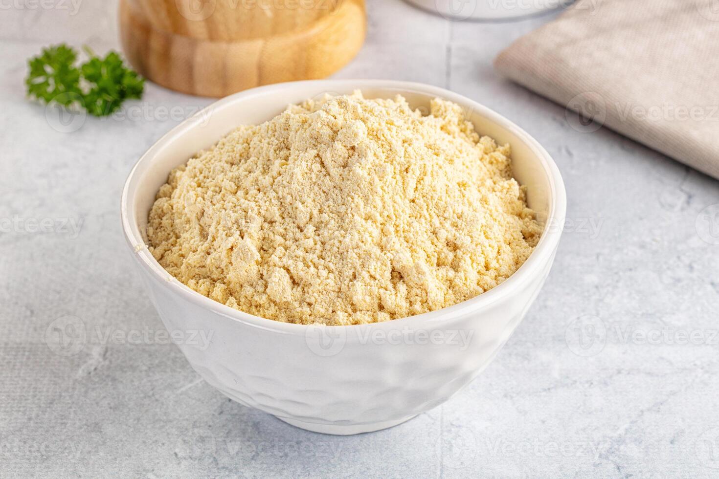 A bowl of flour and a spoon next to a wooden spoon photo