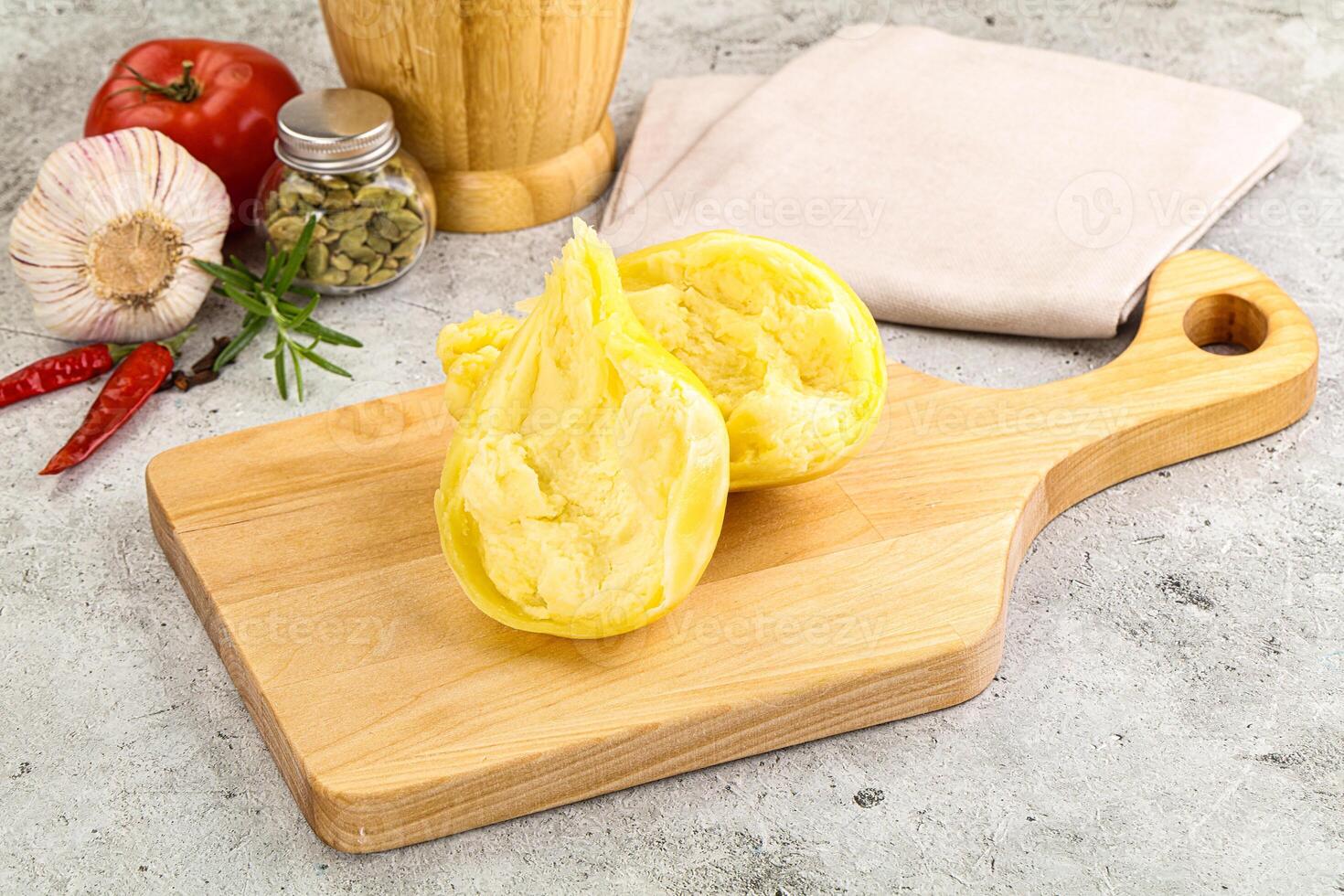 A wooden cutting board with a half peeled potato on it photo