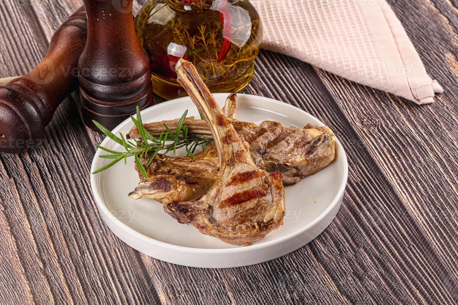 Grilled lamb chops on a white plate on a wooden table photo