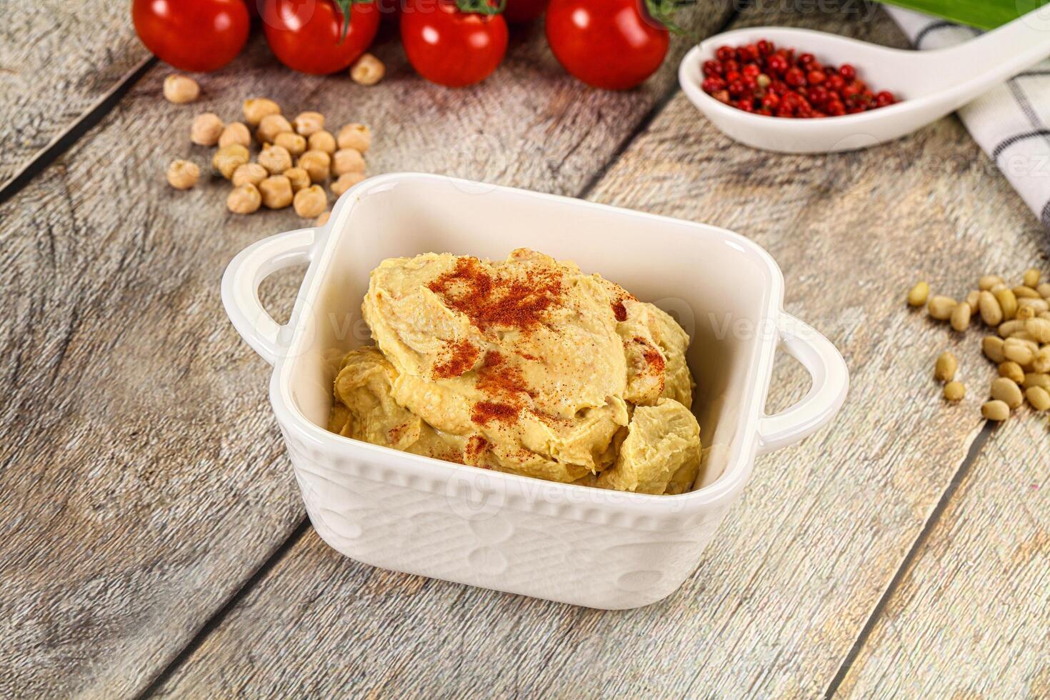 A bowl of hummus with a spoon and a bowl of beans photo