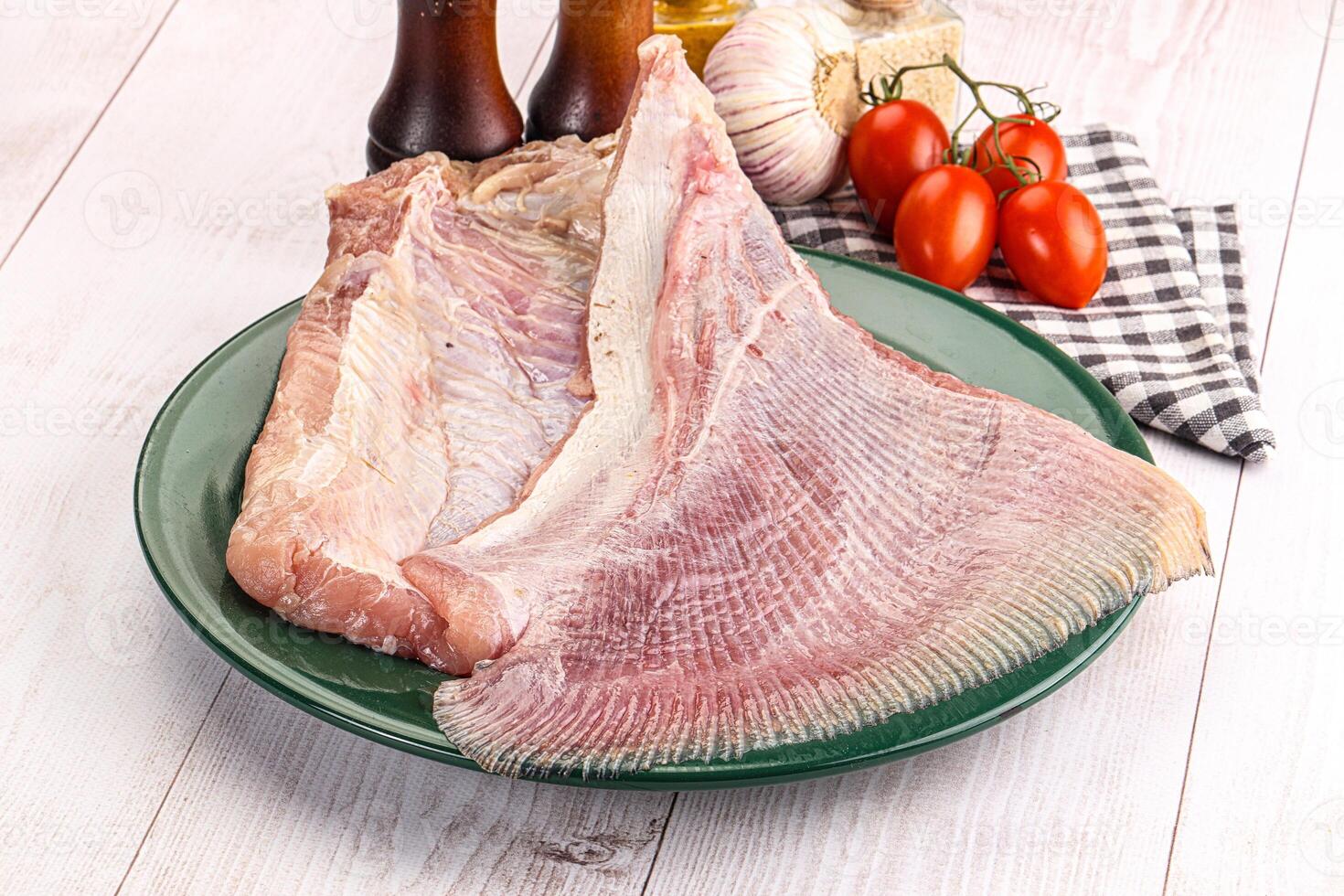 A plate of raw fish on a table with a bottle of ketchup and a bottle of vinegar photo