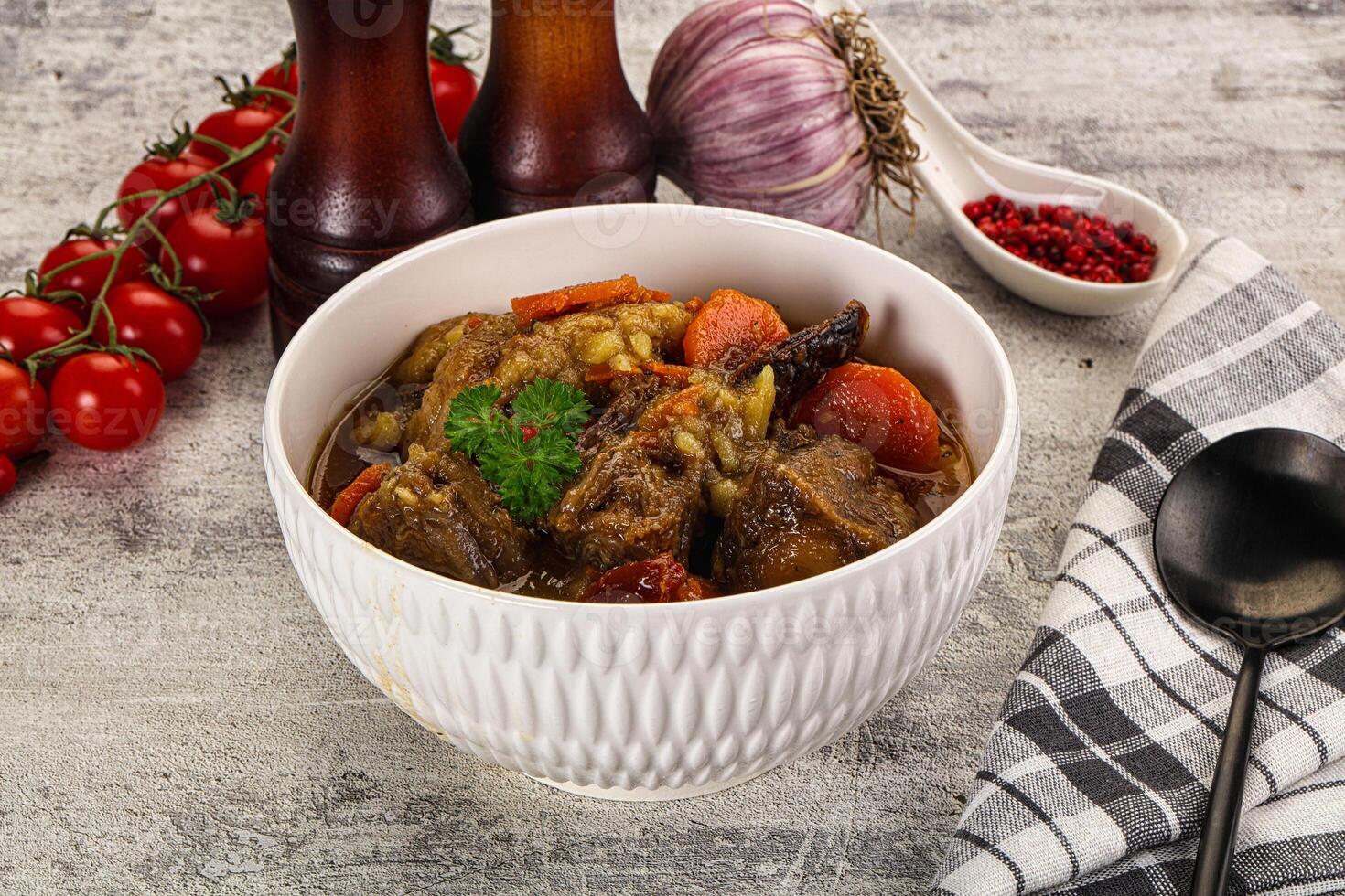 A bowl of stew with vegetables and a spoon photo