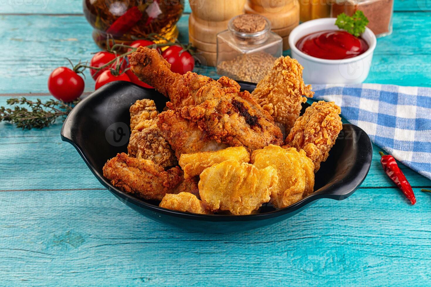Fried chicken and other food in a bowl on a blue table photo