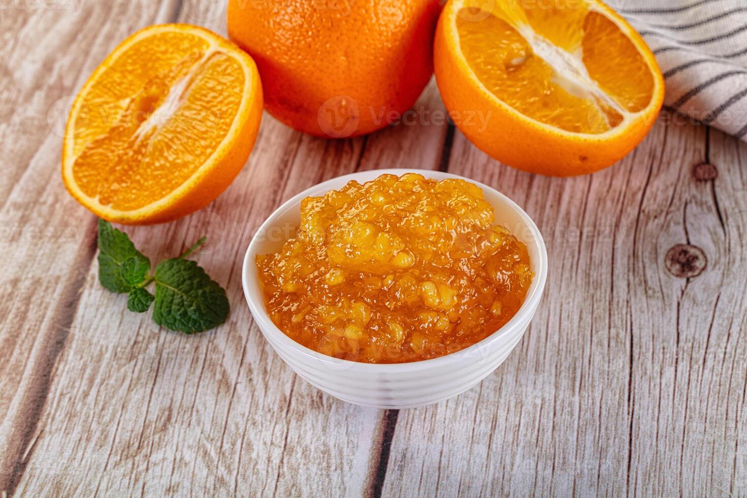 A bowl of orange juice and a half orange on a table photo