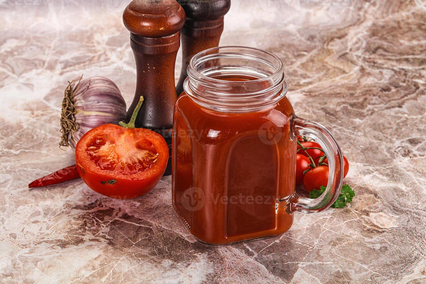 A jar of tomato sauce next to a pepper shaker photo