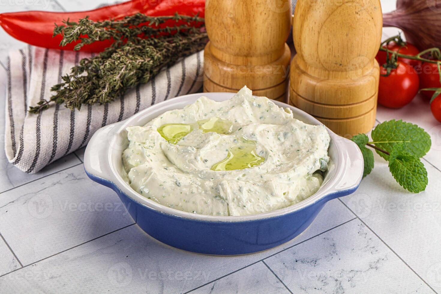 A bowl of dip with a pepper, garlic and tomatoes photo
