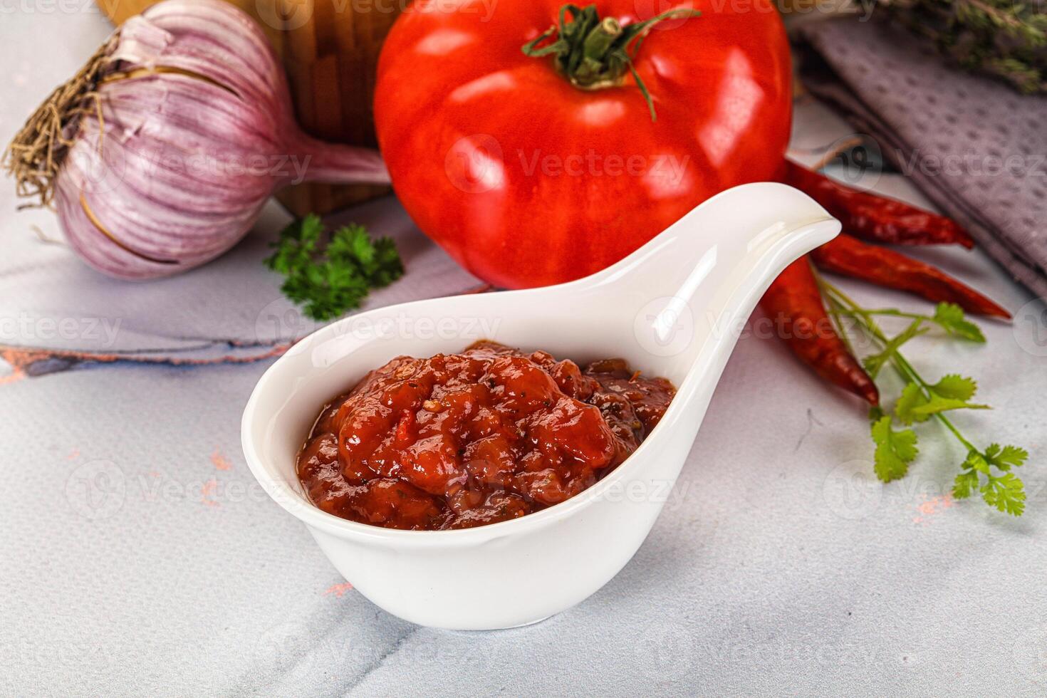 A white spoon with a scoop of tomato sauce photo