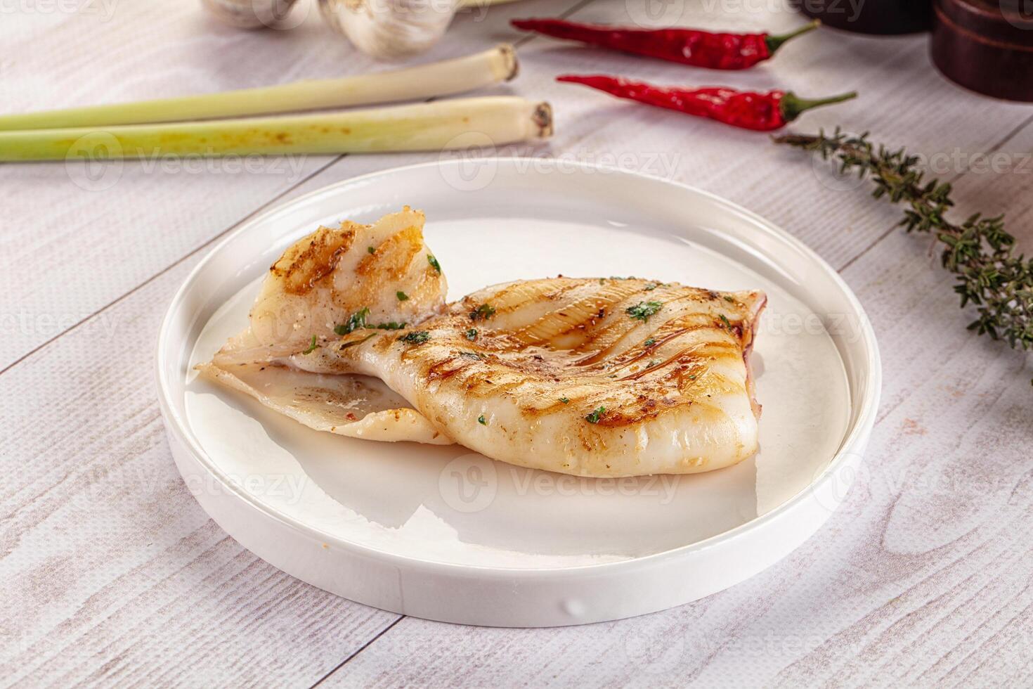 A piece of fish on a white plate with some spices photo