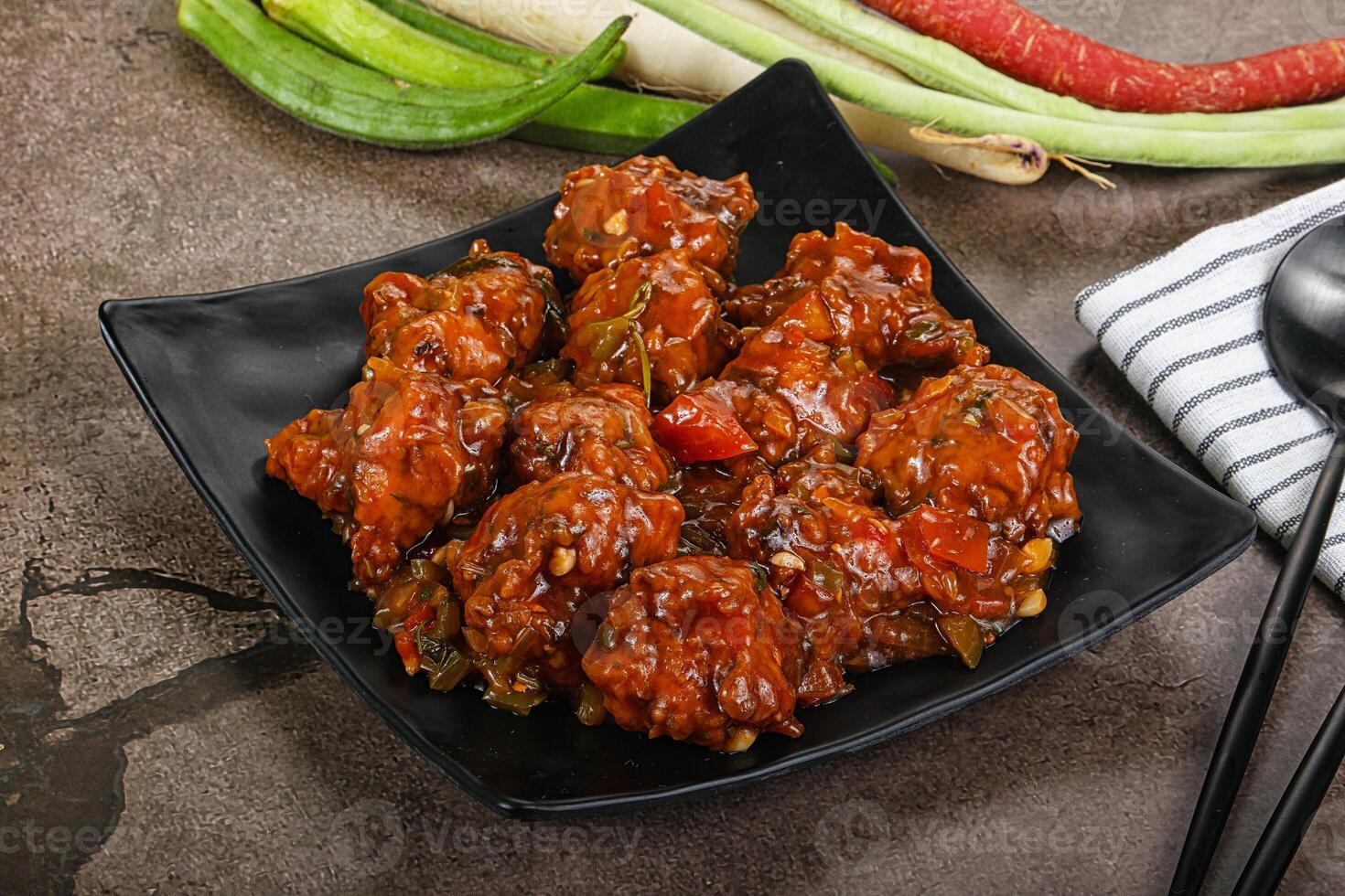 Chicken wings with sauce and vegetables on a black plate photo