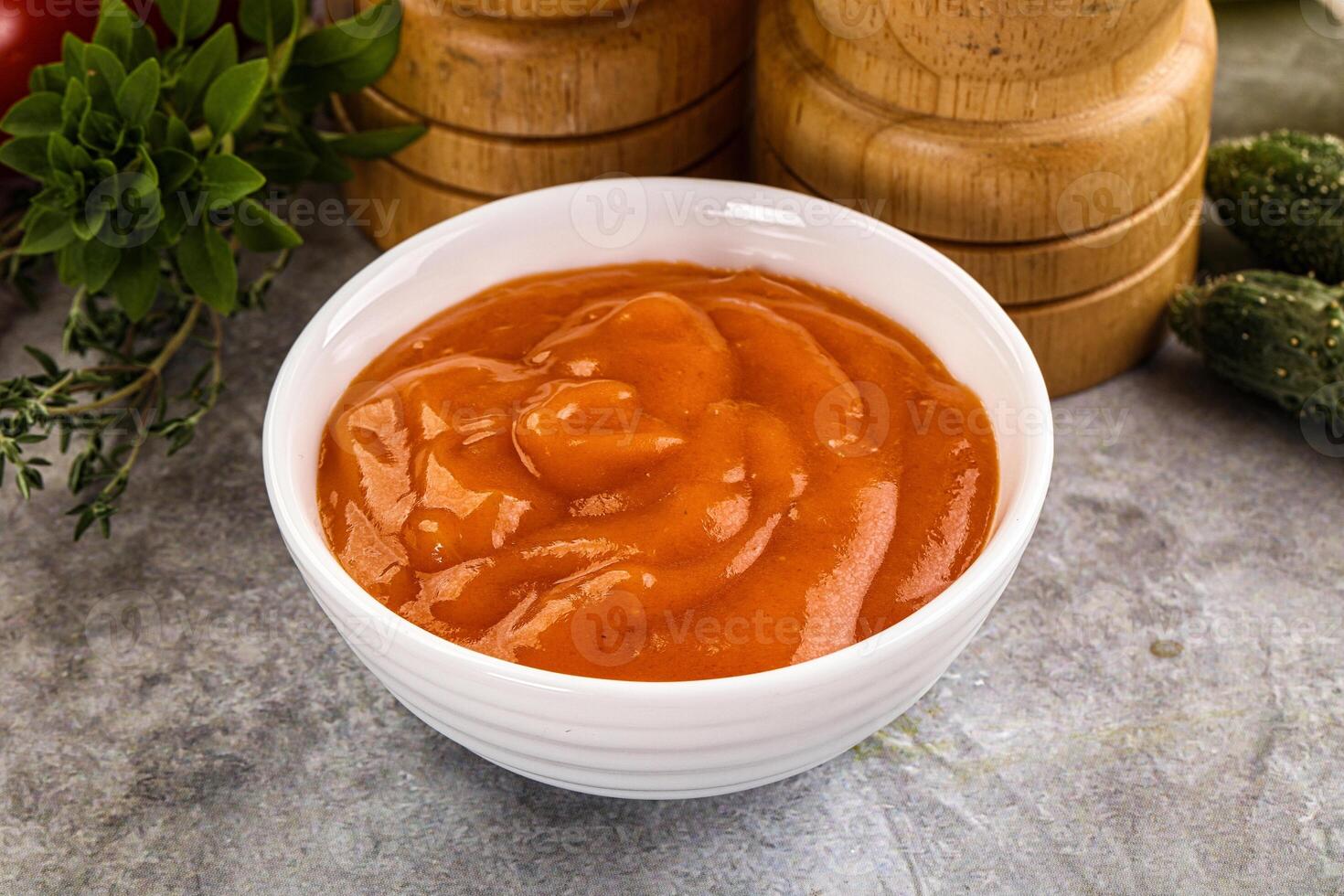 A bowl of tomato sauce next to a pepper grinder photo