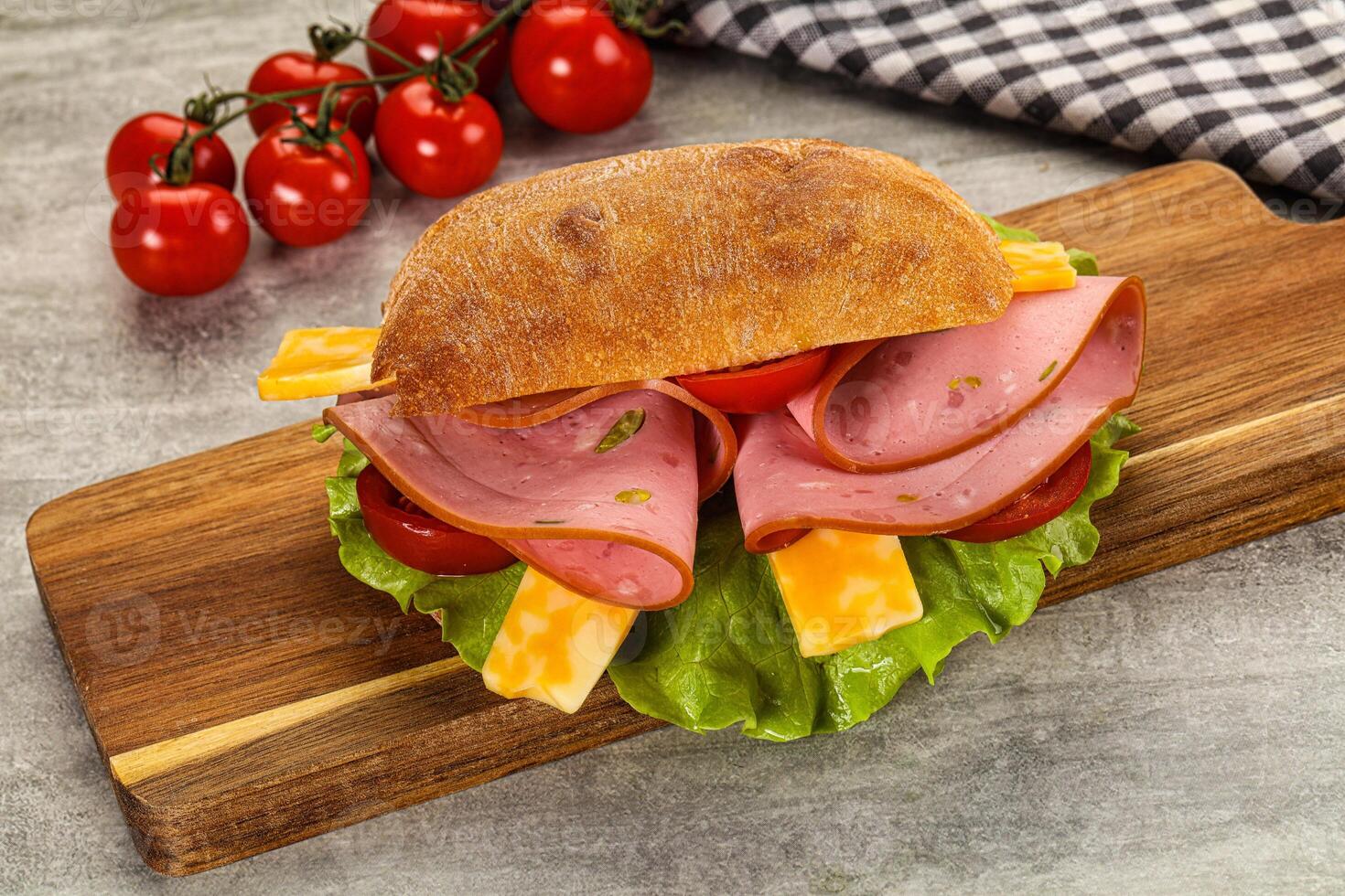 Ham, cheese and tomato sandwich on a wooden cutting board photo