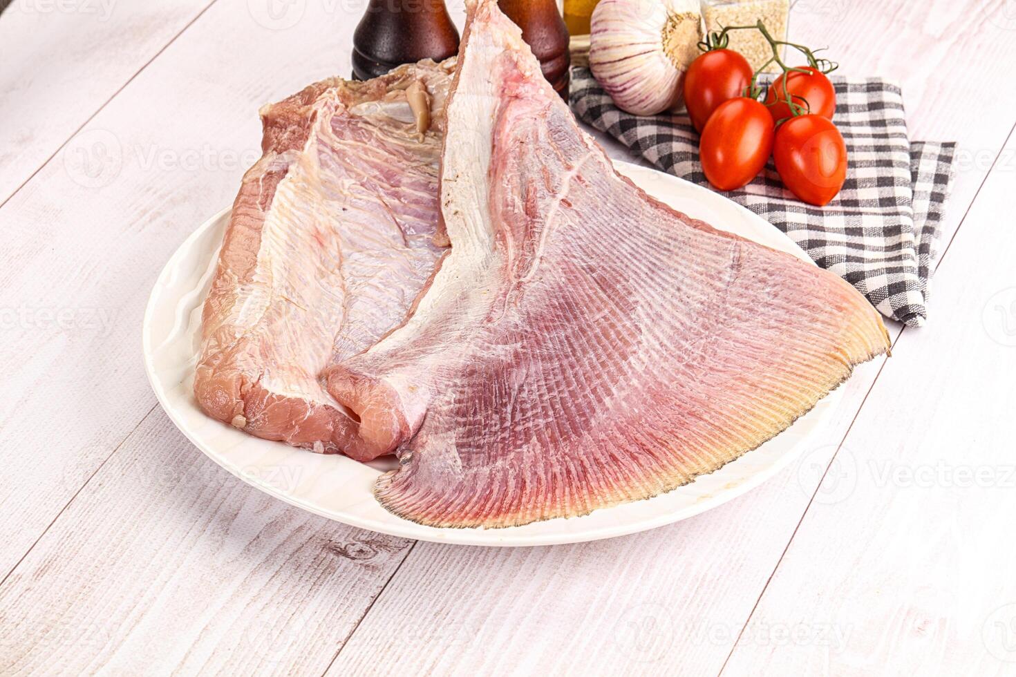 Raw fish fillet on white plate with vegetables and spices photo