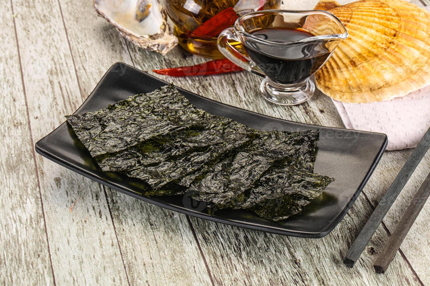 A plate of sushi with a glass of wine and a bowl of seaweed photo