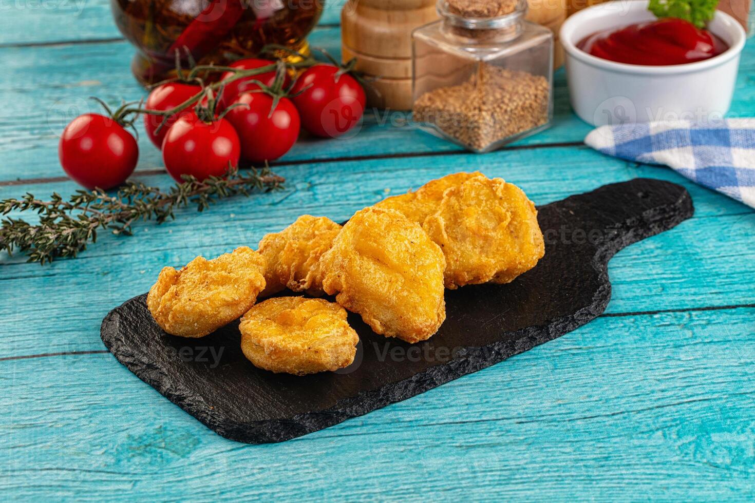 Fried chicken nuggets on a black board with sauce and spices photo
