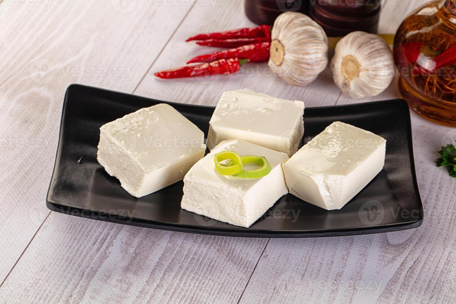 Four pieces of tofu on a black plate photo