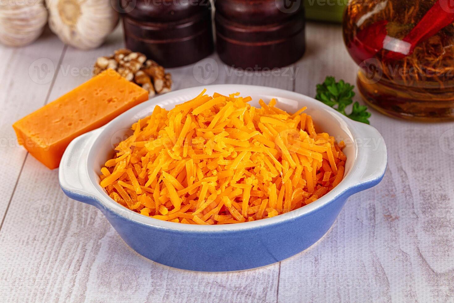 A bowl of shredded cheese next to a bottle of vinegar photo
