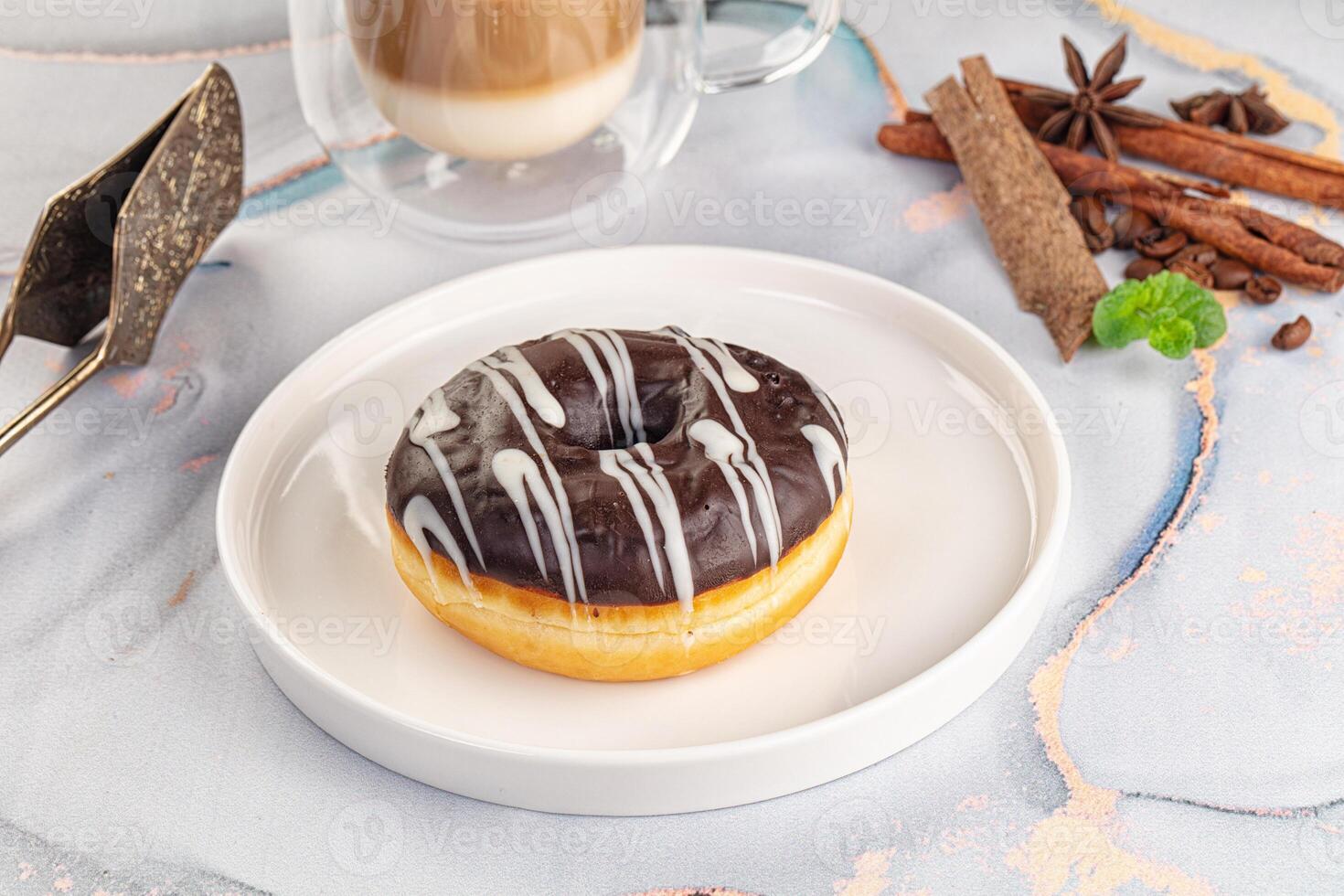 A chocolate donut on a plate with coffee and spices photo