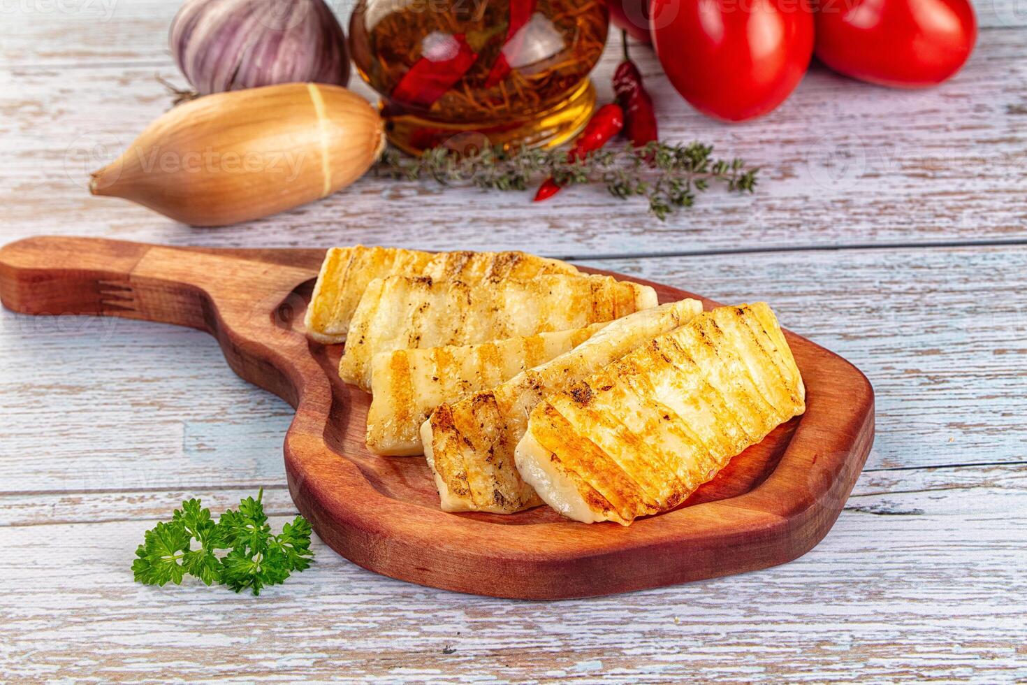 Grilled fish fillet on wooden cutting board with tomatoes and herbs photo