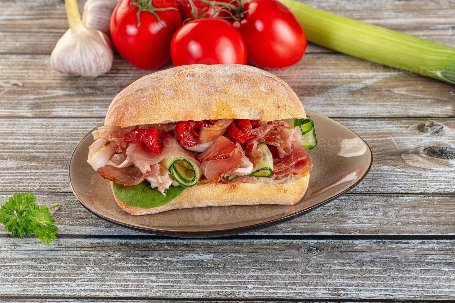 A sandwich on a plate with tomatoes and other vegetables photo