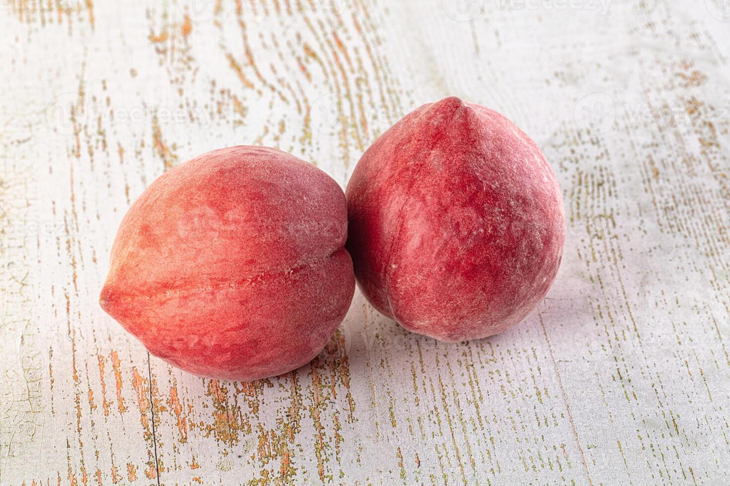 Two peaches on a wooden surface photo