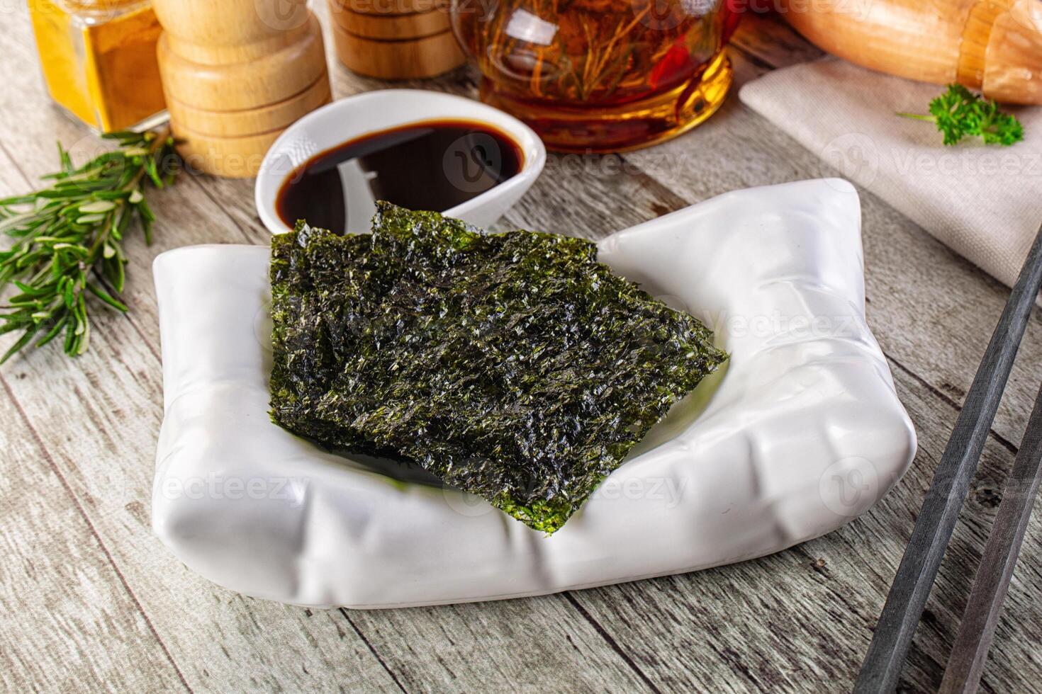 A bowl of seaweed with chopsticks and soy sauce photo
