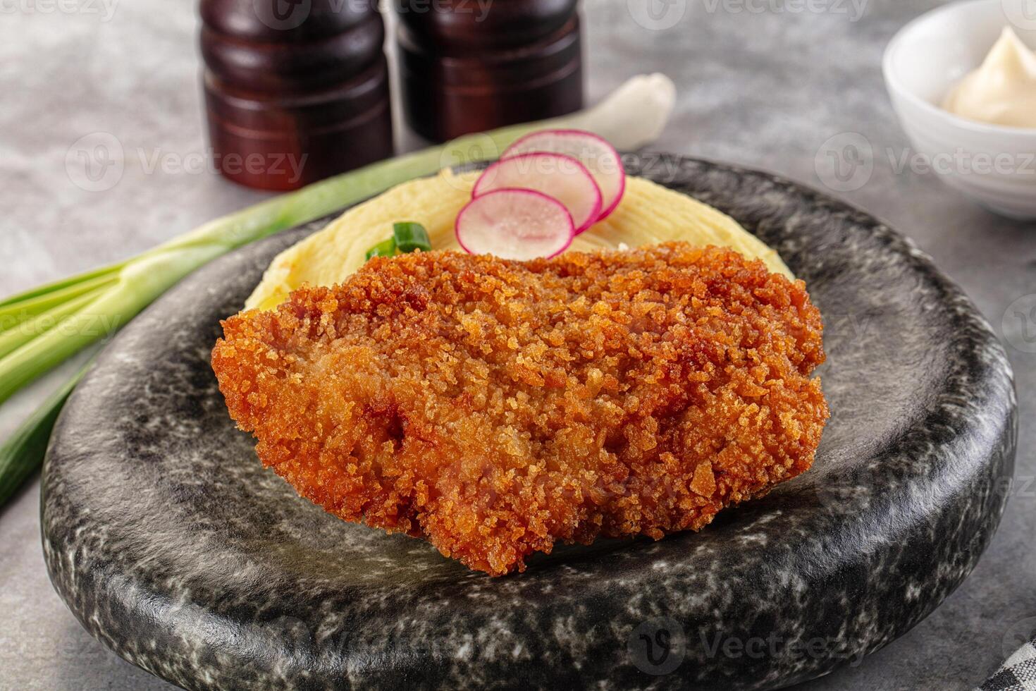 Fried chicken cutlet with pickles and onions on a stone plate photo