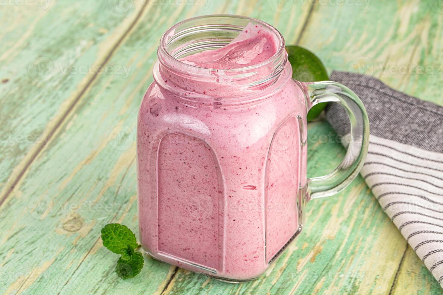 A pink smoothie in a glass jar on a wooden table photo