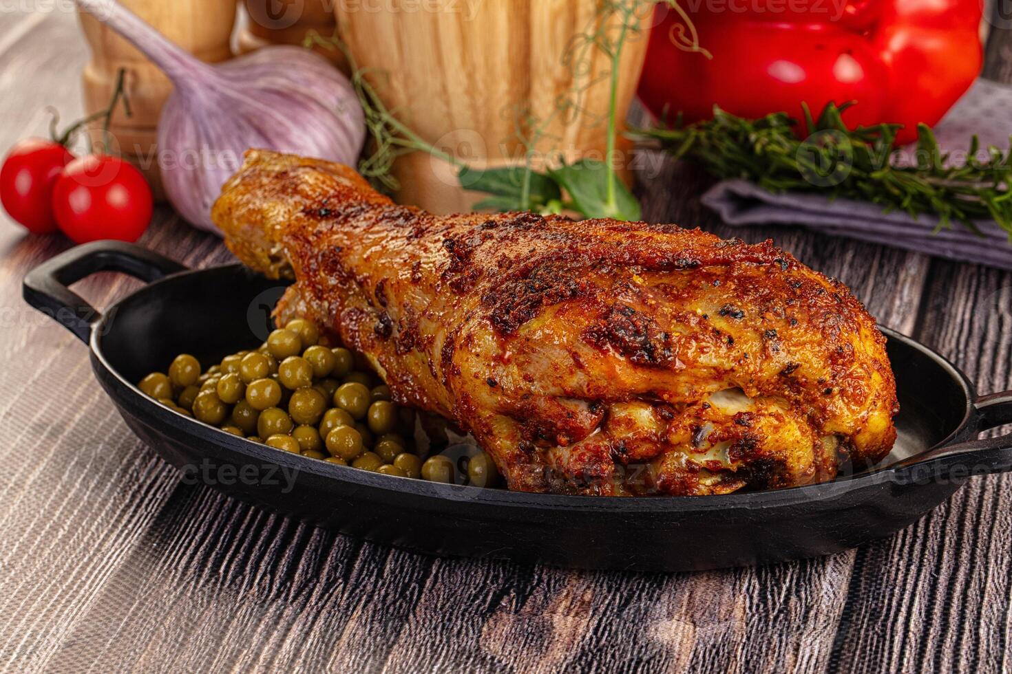 A large chicken in a pan with peas and tomatoes photo
