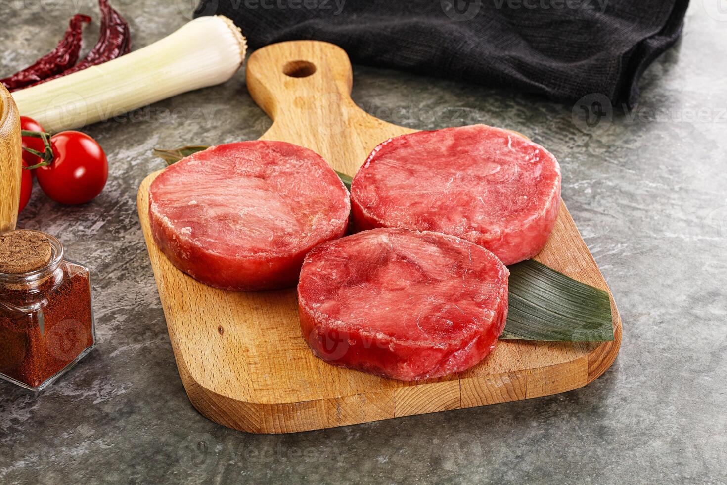 Three raw beef steaks on a cutting board with spices photo