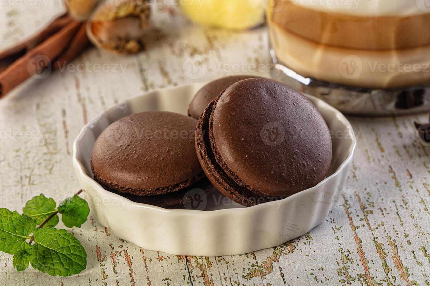 A bowl of chocolate macarons and a cup of coffee photo