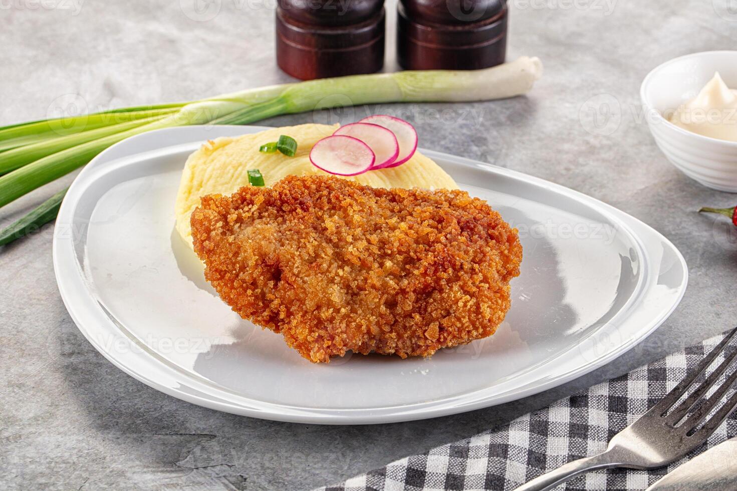 A plate with a fried chicken cutlet and mashed potatoes photo