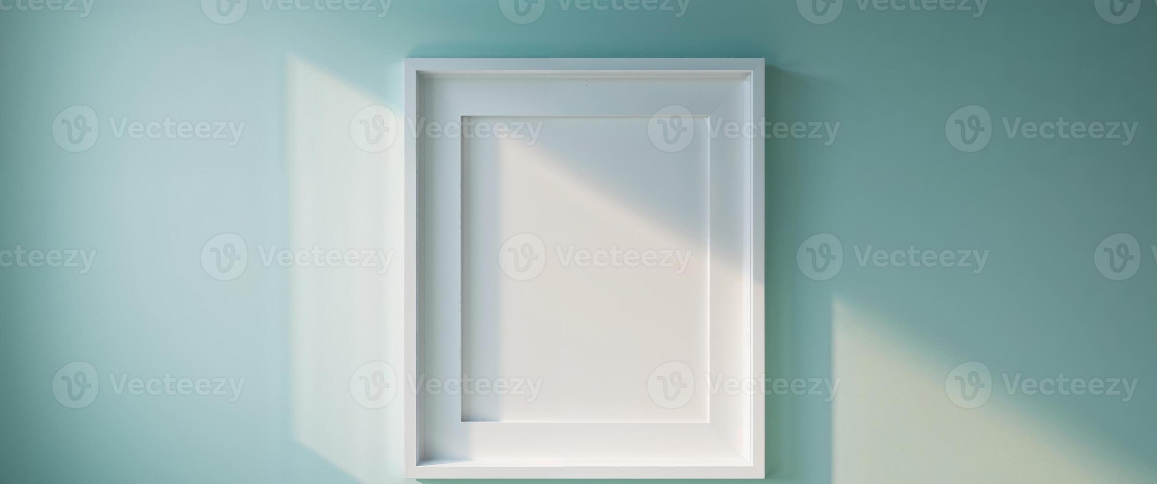 Empty white picture frame on a light teal wall. photo