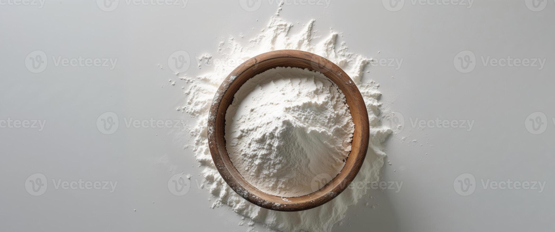 A wooden bowl overflowing with white flour on a surface. photo