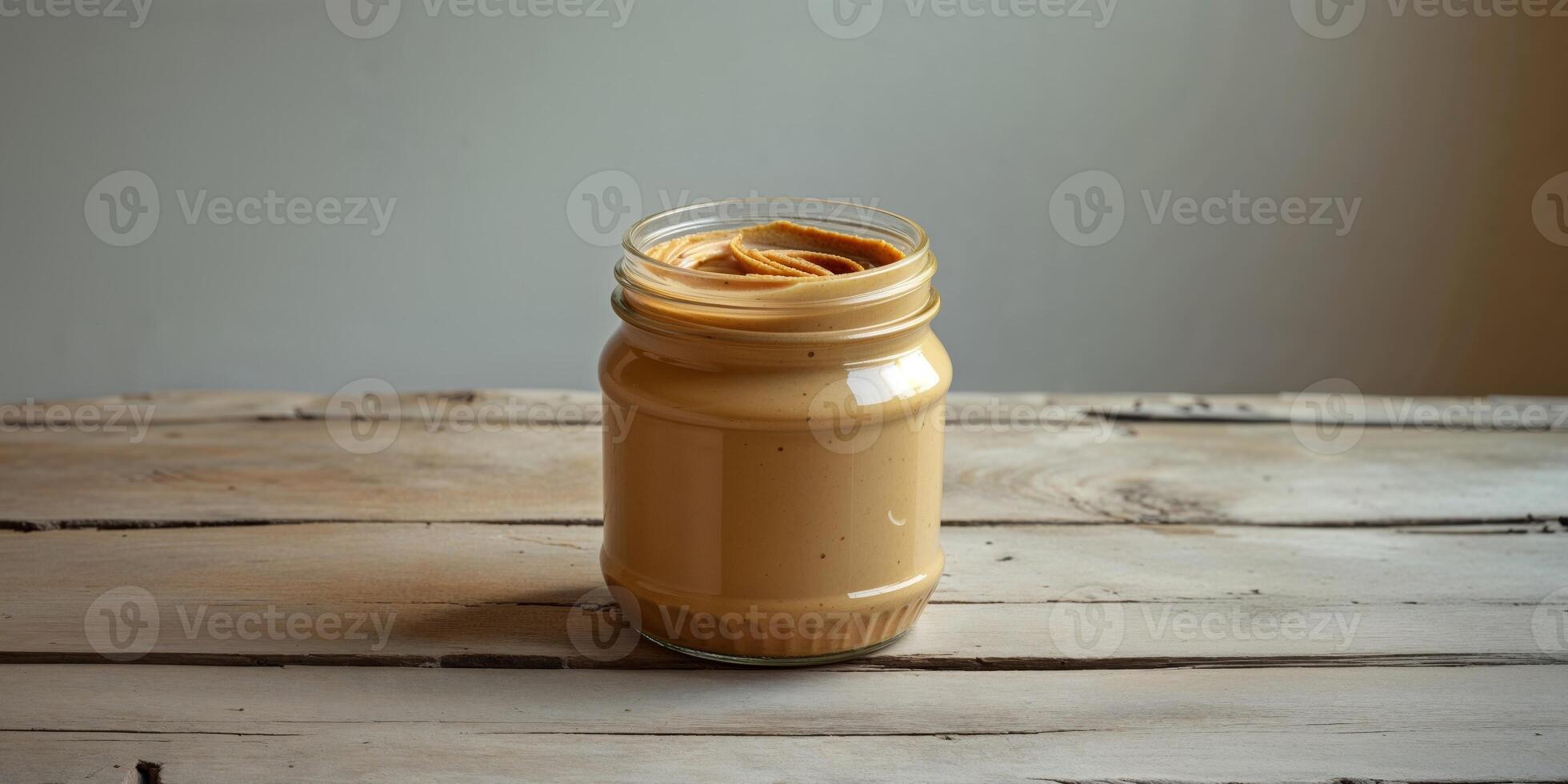 A jar of peanut butter sitting on a wooden table photo