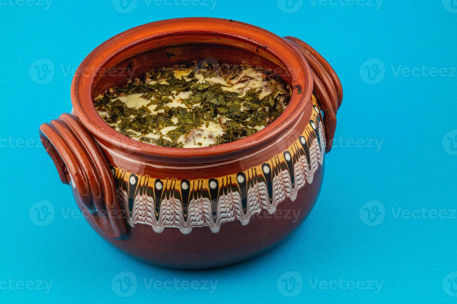 Traditional Mexican dish served in a colorful clay pot on a blue background photo