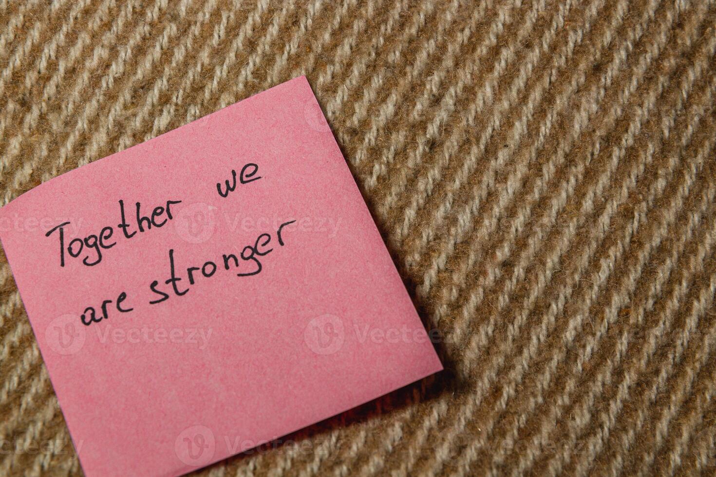Together we are stronger written on a pink sticky note on carpet photo