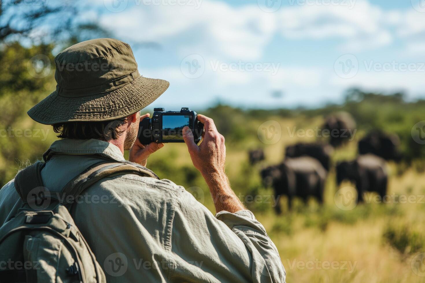Caucasian male adult photographing elephants in african savanna photo