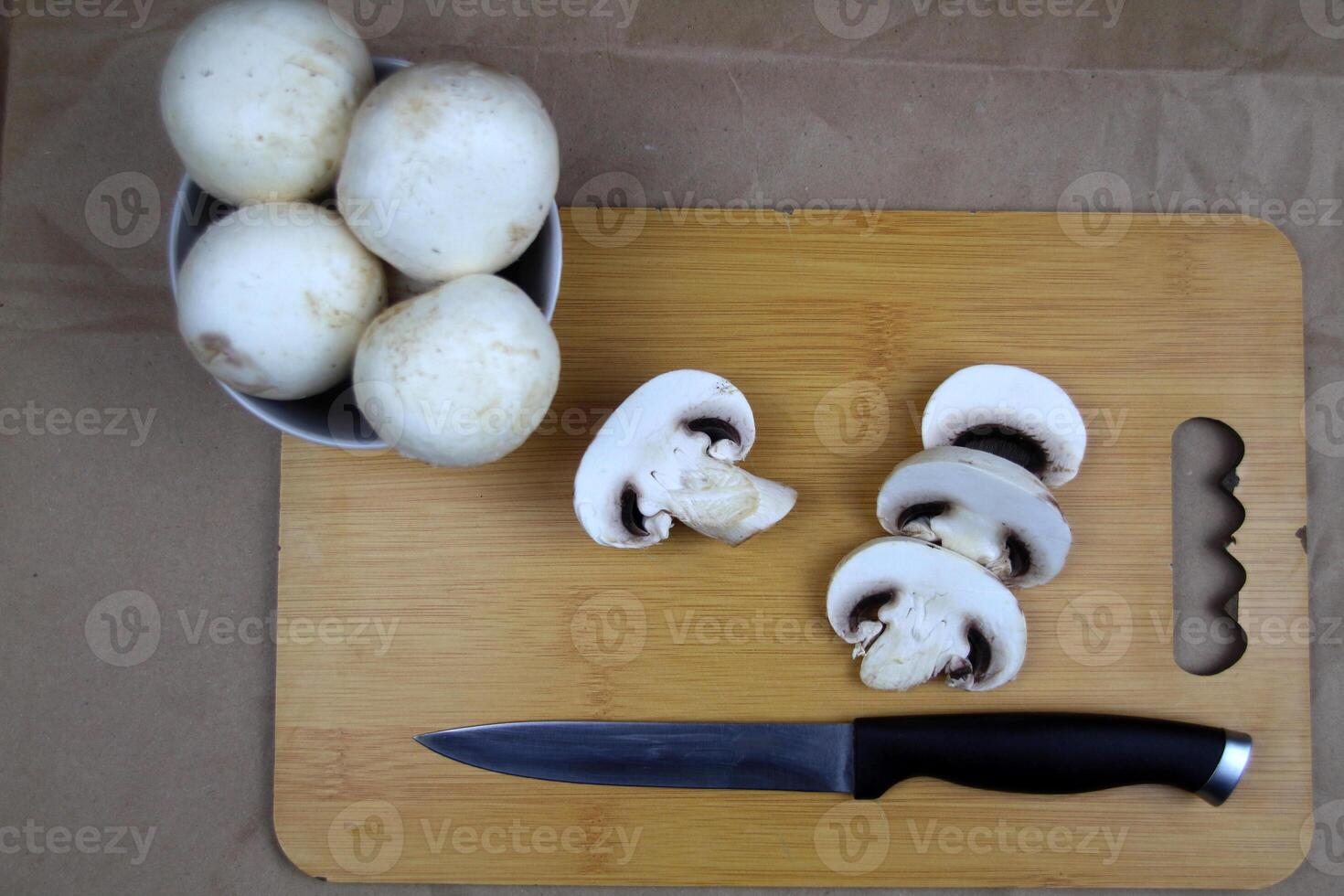 There are mushrooms on the plate, a knife and slices of champignons are on the board next to it photo