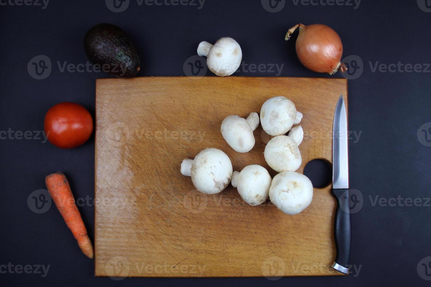 Cooking a vegetable dish. There are mushrooms on the board and fresh vegetables nearby photo