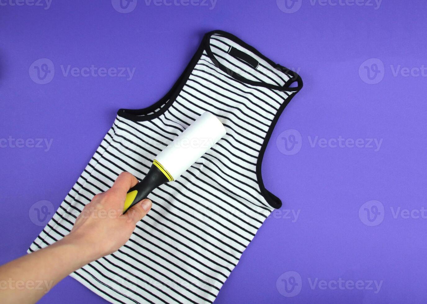Woman's hand using a clothes roller to keep her T-shirt clean photo