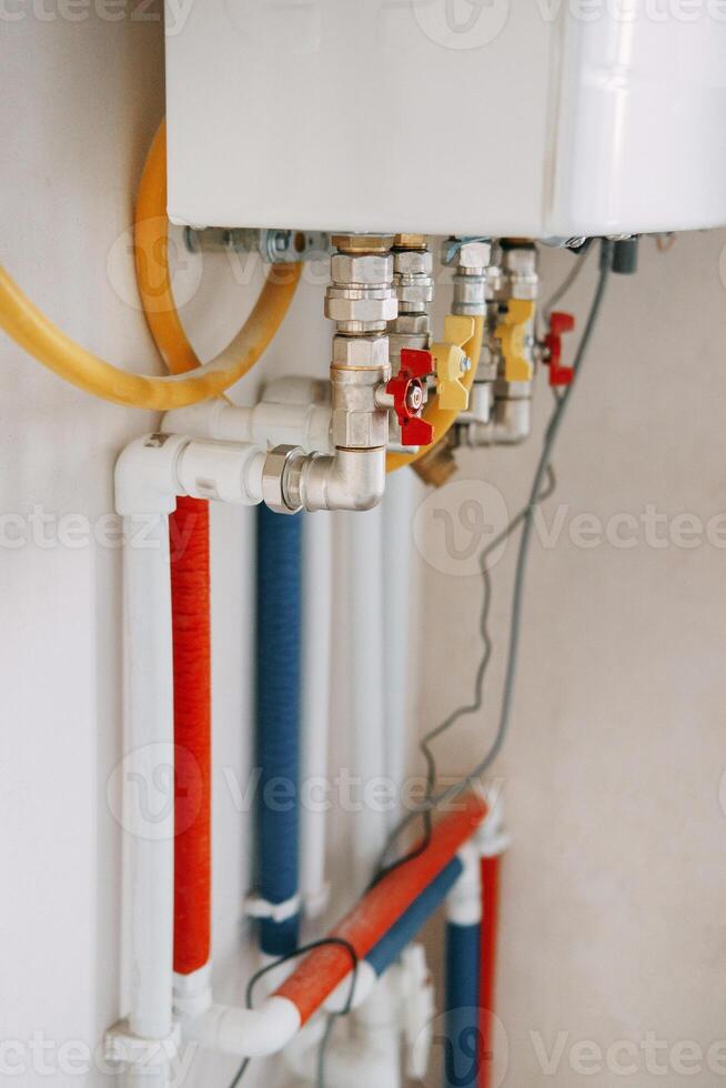 Installation of gas boiler with colored pipes equipped with valves and connectors for efficient supply of hot and cold water in the residential water supply system photo