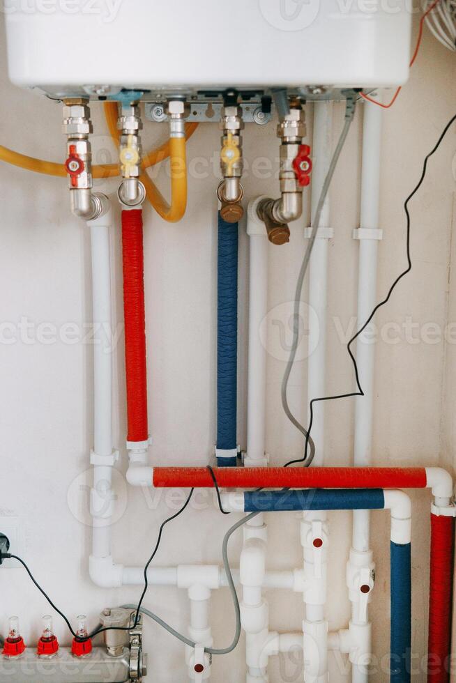 Installation of gas boiler with colored pipes equipped with valves and connectors for efficient supply of hot and cold water in the residential water supply photo