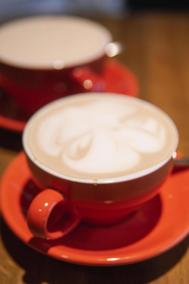 Two red cups filled with coffee served wooden table photo