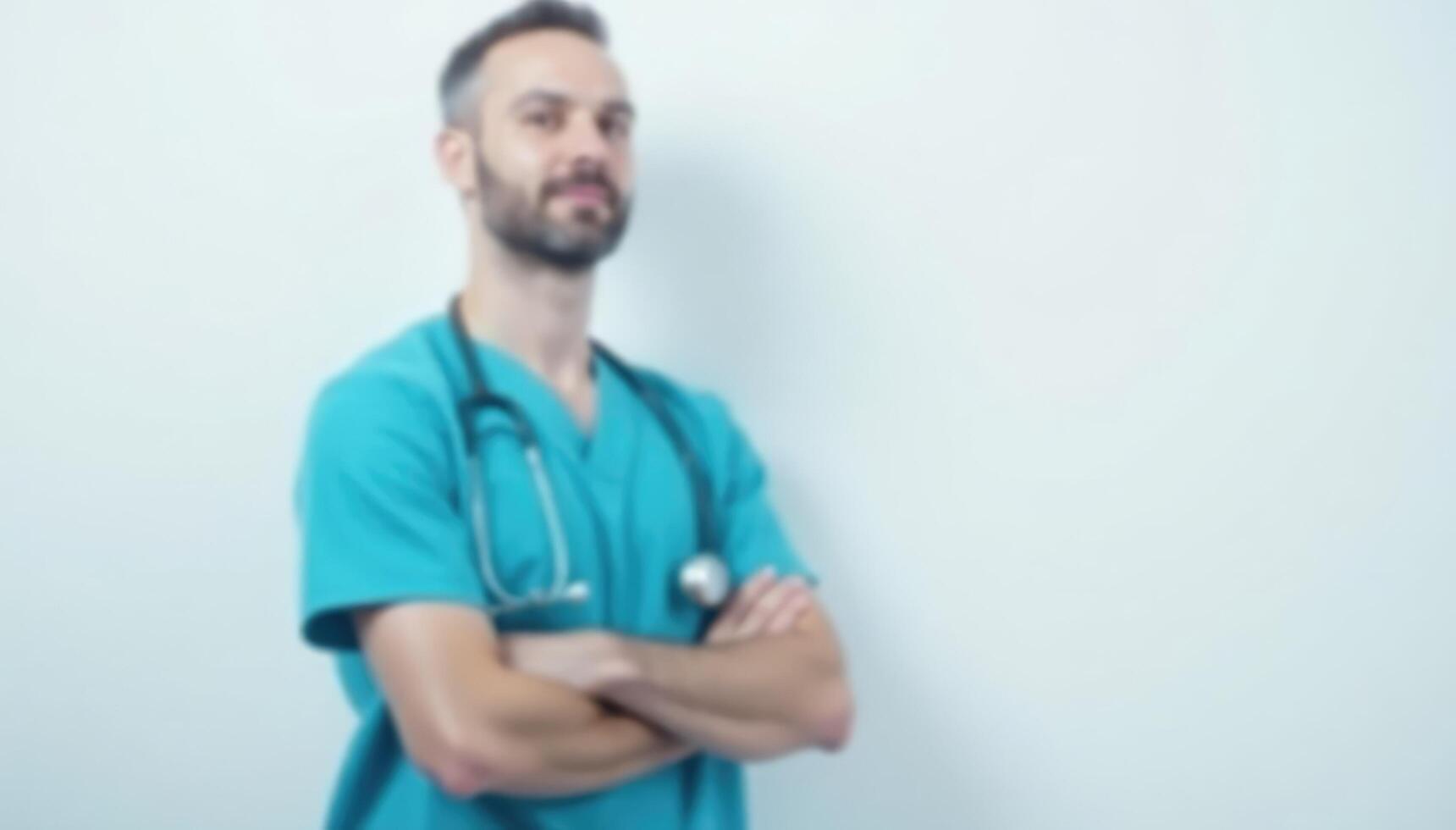 A male doctor standing in front of a white wall photo